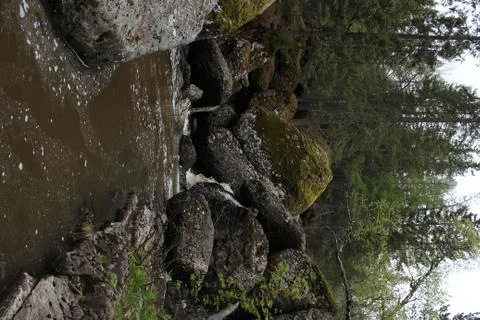 A mountain river waterfall flows through a river bed through huge boulders with Stock-Fotos