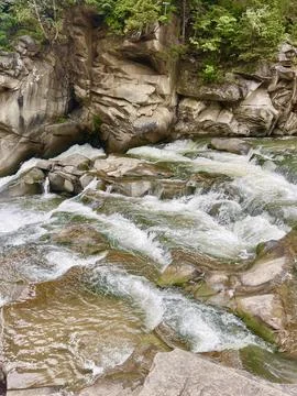 A mountain river with a waterfall. Streams of water with foam falling down Foto stock