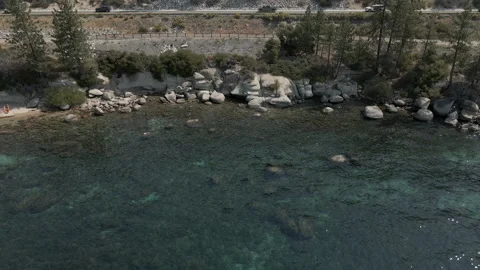 Mountain road along crystal clear lake cinematic footage Stock Footage 163685392
