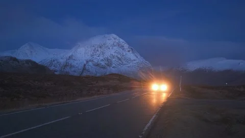 The mountain road heading towards the snow-covered mountains and the lights of Stock Footage 236101889