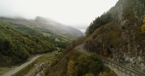 Mountain road hugs the side of the cliff as it ascends drone aerial 4k Stock Footage 125757358