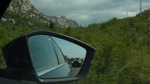 Mountain road reflected in car side mirror, showing following vehicle Stock Footage 299895641