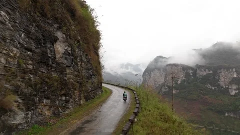 Mountain road with a steep drop off the edge, motorbike travelling around Stock Footage 267076851