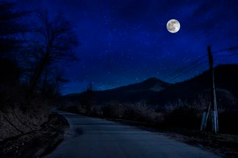 Mountain Road through the forest on a full moon night. Scenic night landscape Stock-Fotos