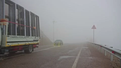 Mountain road with vehicles driving through dense fog 스톡 동영상 343087534