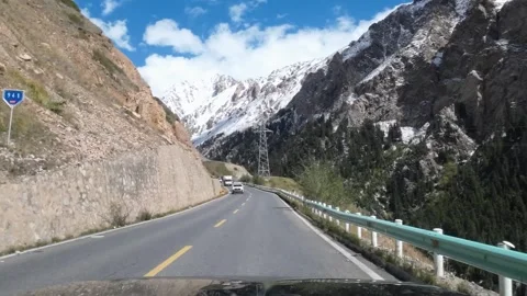 Mountain road view toward snowy peaks in Xinjiang China Stock Footage 337860528