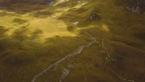 Mountain road winding between grassy hills and rocks. Clouds' shadows and 库存影片 82844181