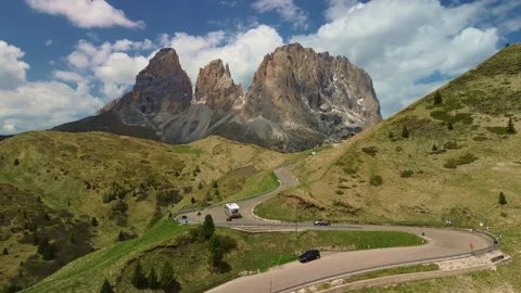 Mountain road winding through green alpine hills under bright daylight 스톡 동영상 337079369