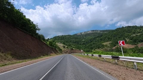 Mountain road winds under partly cloudy sky Stock Footage 340079044