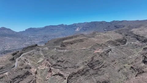 Mountain roads winding through steep volcanic terrain under blue sky Stock Footage 310683194