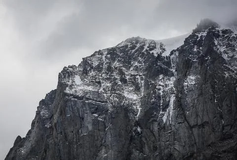 Mountain rocky range with snow in the clouds close-up Stock Photos