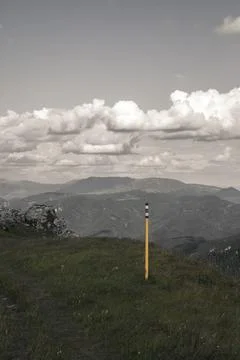 Mountain scenery with navigation trail marker pole placed on grassy slope u.. Stock Photos