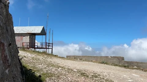 Mountain Service Hut Above the Clouds with Fast Moving Clouds Stock Footage 341819933