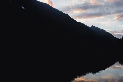 Mountain in shadow with a reflection in a  lake. Sunset in Alps,Austria. Stock Photos