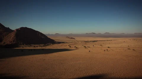 MOUNTAIN SHADOWS RECEDE FROM VAST GRASSLAND UHD 4K Stock Footage 45343099