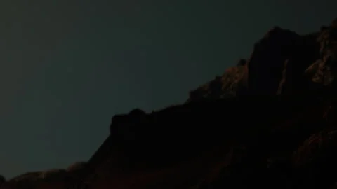 Mountain silhouette at night with dark sky and faint light Stock Footage 339867254