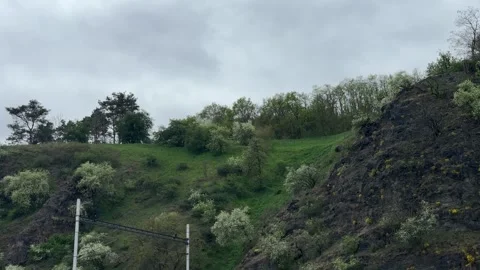 Mountain slope features natural rock formation, budding tree, white blossom Stock Footage 333163805