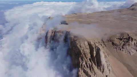 Mountain slopes embracing soft clouds, revealing rugged peaks reaching luminous Stock Footage 304531460