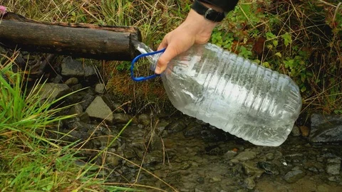 Mountain spring. draw water in a big plastic container Stock Footage 82927606