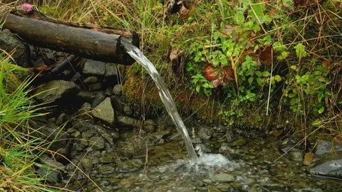 Mountain spring. flow of water from gutter to stones Stock Footage 83108904