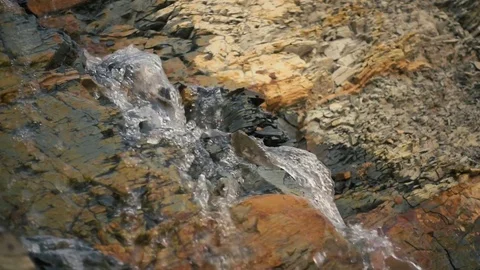 A mountain spring flows down slow mo Stock Footage 81558966