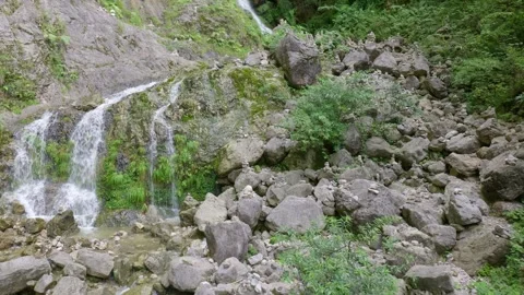 Mountain spring water divides into three small waterfalls Stock Footage 313544673