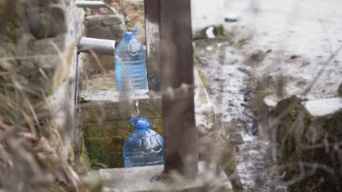 Mountain spring water filling up two plastic bottles Stock Footage 100889948