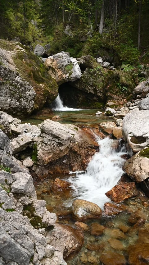 A mountain stream in autumn with a waterfall in the background, vertical shot Video stock 260872278