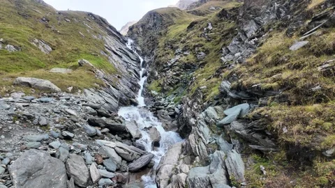 Mountain stream cascading through a rocky alpine gorge below Grossglockner Stockbeeldmateriaal 346604364