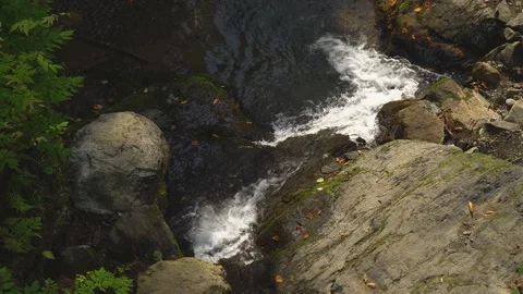 Mountain stream creating white foam runs into dark lake Stock Footage 116870578