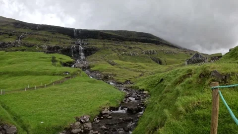 Mountain stream flowing from a cascading waterfall in Saksun, Faroe Islands Stock-Footage 339383269