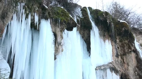 Mountain stream flowing over a frozen waterfall Stock Footage 60446992