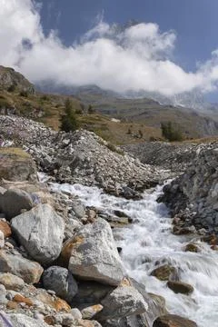 Mountain stream flowing over rocks in matterhorn valley Stock Photos