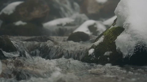 Mountain stream flowing over snowy mossy rocks Видео 331570344
