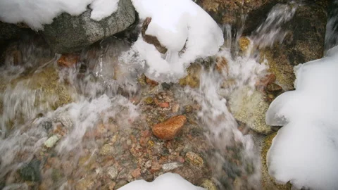 Mountain stream flowing over snowy rocks in winter Vidéo 331793345