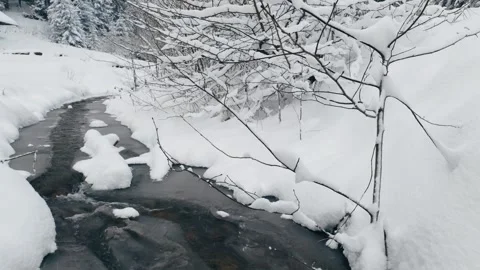 Mountain stream flowing through deep fresh snow and winter forest 스톡 동영상 328410194