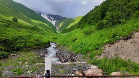 Mountain stream flowing through green valley landscape 動画素材 346319682