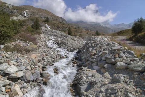 Mountain stream flowing through rocky alpine landscape Stock Photos
