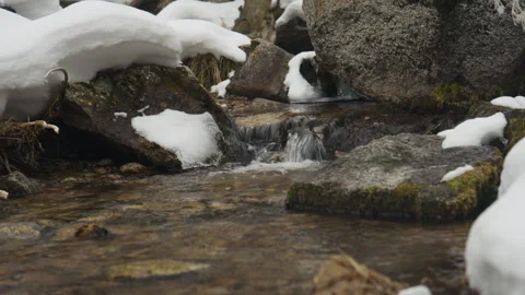 Mountain stream flowing through snow covered rocks Stock Footage 331798544