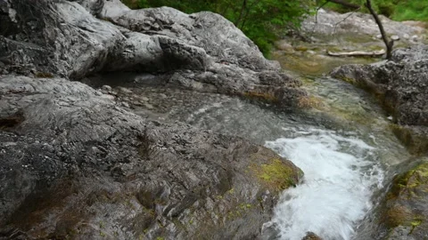 Mountain stream flows between rocks into a pool Stock Footage 211466743