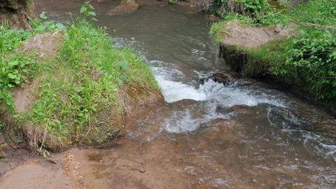A mountain stream flows into a mountainous cold river in a rocky area. Stock-Footage 171233639