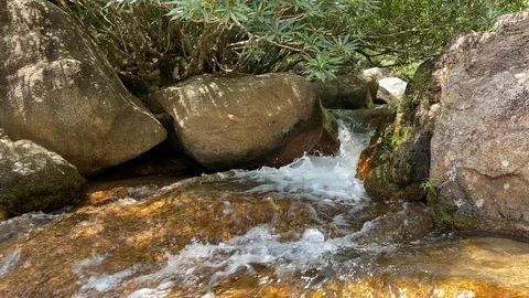 A mountain stream flows through large stones, foam from the flow of water Stock Footage 126287446
