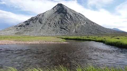 A mountain stream flows through the valley against the backdrop of the mountains Stock Footage 93953201