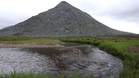 A mountain stream flows through the valley against the backdrop of the mountains Vidéo 93954259