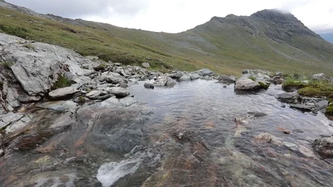 A mountain stream flows through the valley against the backdrop of the mountains Video stock 93954299