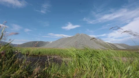 A mountain stream flows through the valley against the backdrop of the mountains Vidéo 93954317