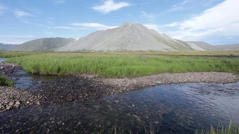 A mountain stream flows through the valley against the backdrop of the mountains Stock Footage 93954328