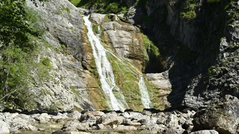 The mountain stream in front of a picturesque waterfall in the alps 스톡 동영상 260845398