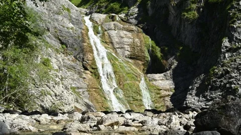 The mountain stream in front of a picturesque waterfall in the alps Stock Footage 260845422