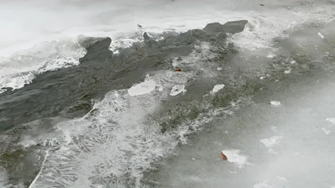 Mountain stream goes beneath the ice and melts it. Stock Footage 147482326